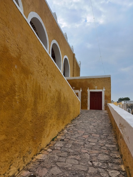 A cobblestone pathway leading to a building with a red door and arched windows. 4
