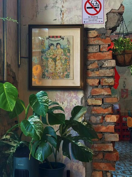 A wall with a framed picture, a brick wall, and a potted plant. 1