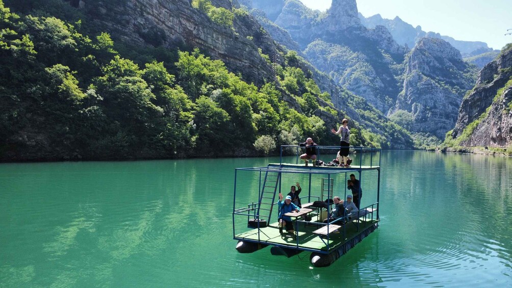 A floating platform with people on it, surrounded by a calm river and steep cliffs. 1