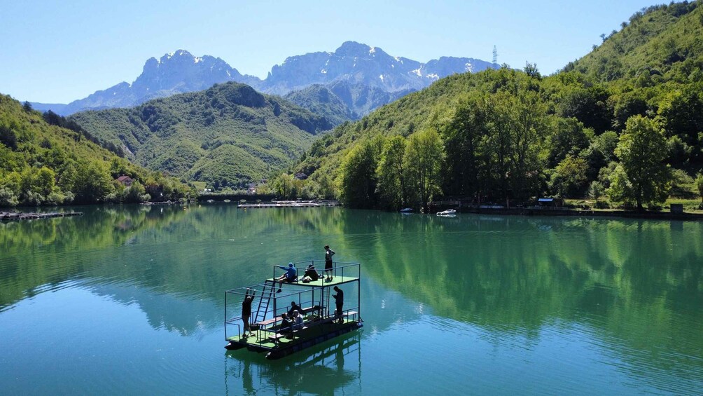 A green boat on calm water with mountains in the background. 2