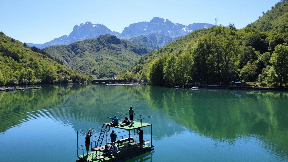 A calm lake with a floating platform where people are engaging in water activities. 4
