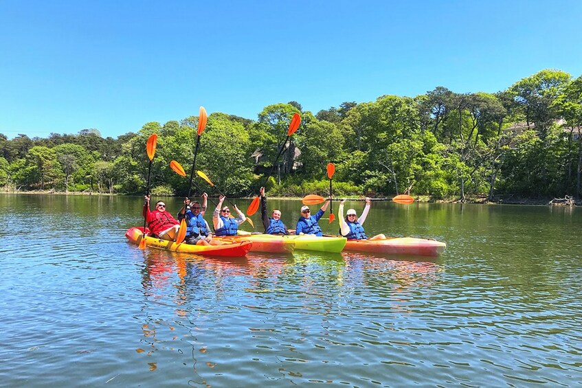 A group of people in colorful kayaks on a calm lake with trees in the background. 2