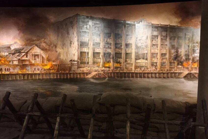 A large building with a fire in the background, a dock with boats, and a body of water. 1