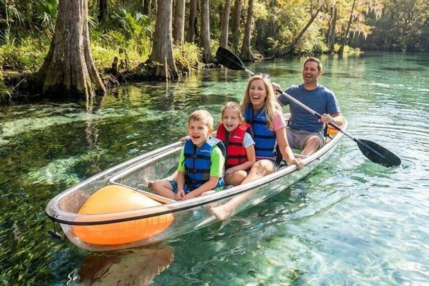 A family in a transparent canoe on a clear river surrounded by trees. 2