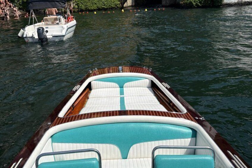A wooden boat with turquoise cushions and a white deck, floating on calm water. 3