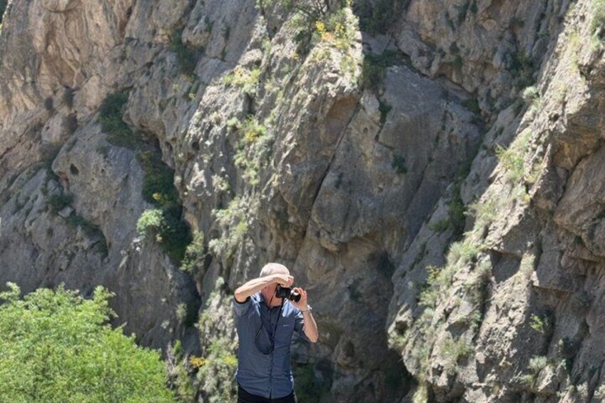 A person taking a photograph with a camera in a rocky outdoor setting. 2