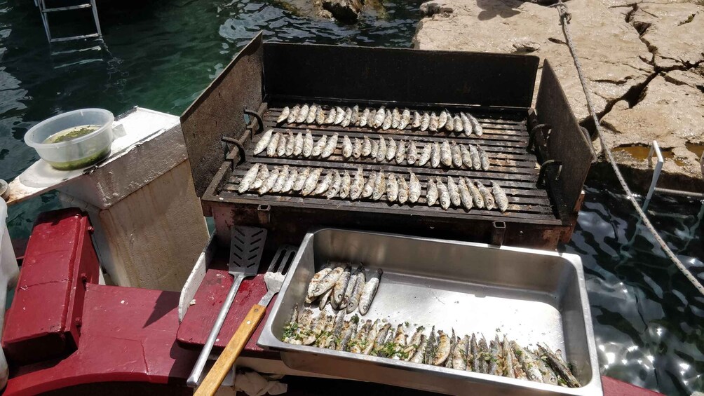 A portable grill with fish being cooked on it. 3