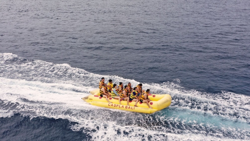 A group of people on a yellow inflatable raft labeled 'CASPLA BALI' in the ocean. 5