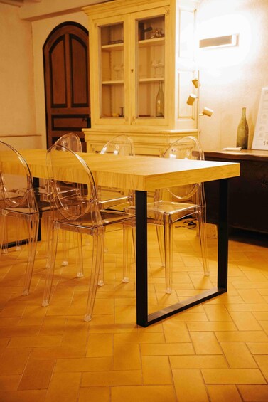 A dining table with clear chairs, a wooden cabinet, and a lit wall. 5