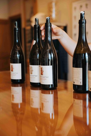 Three bottles of wine with labels on a reflective surface. 3