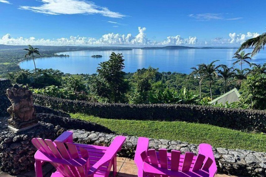 A tropical landscape with a clear view of a large body of water, palm trees, and a stone wall. 3