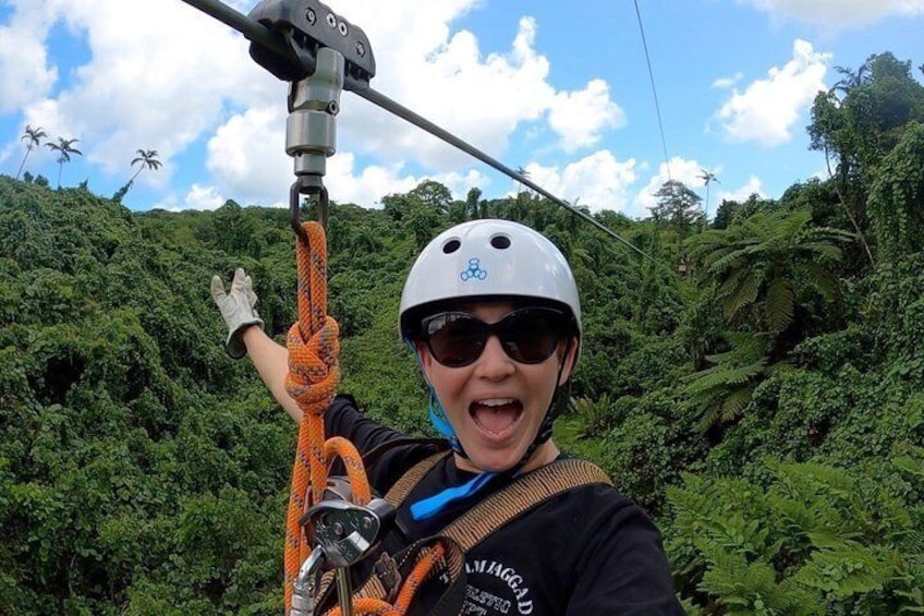 A person with a helmet and harness, holding an orange rope, in a forested area. 5
