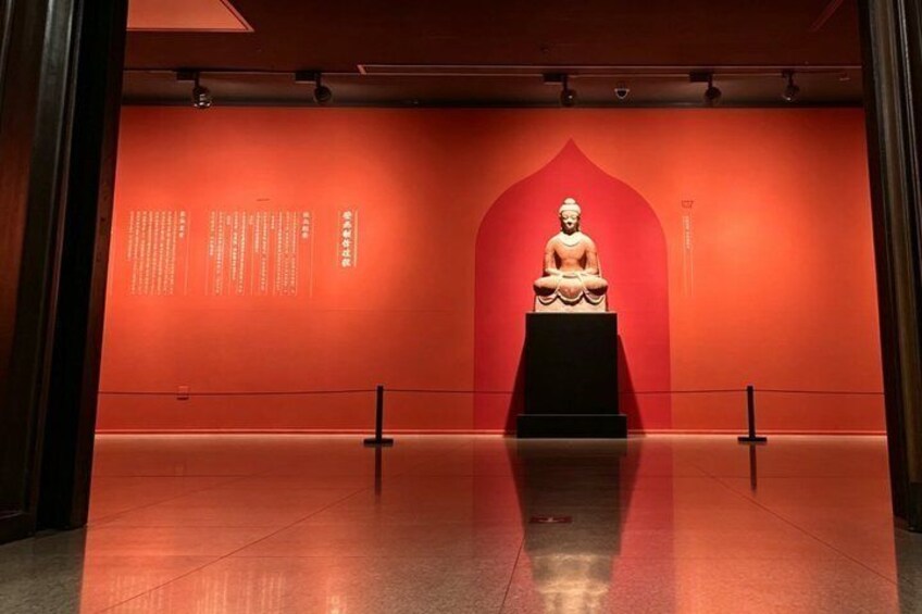 A statue in a red-lit room with informational text on the walls. 5
