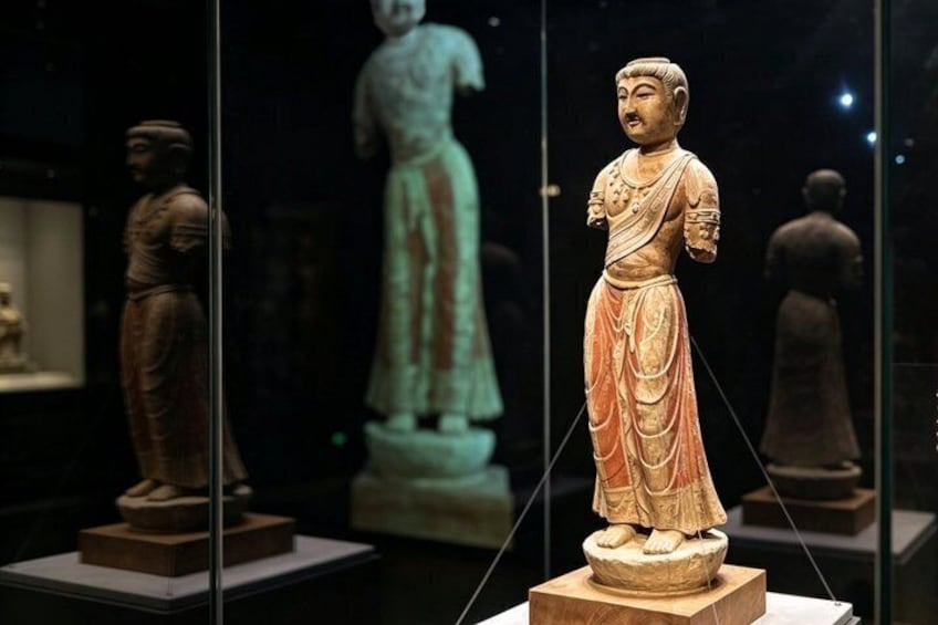 A museum display with ancient statues, including a prominent figure in orange attire. 4