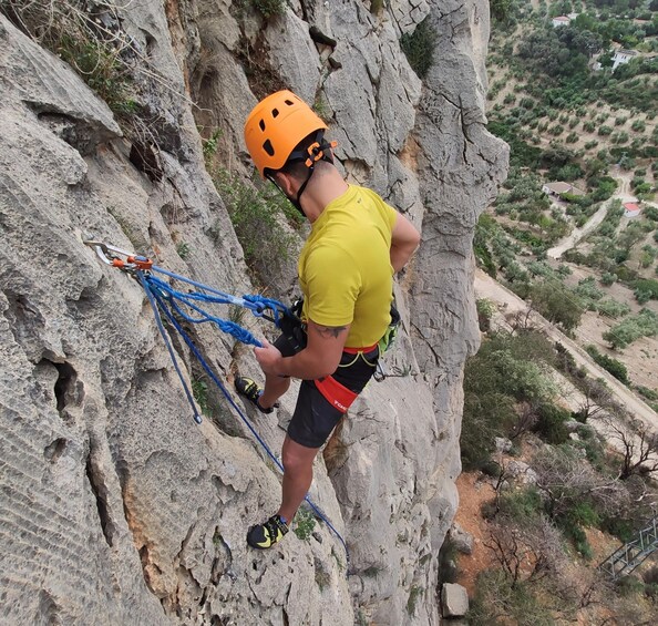 A person climbing a rocky cliff with climbing gear. 2