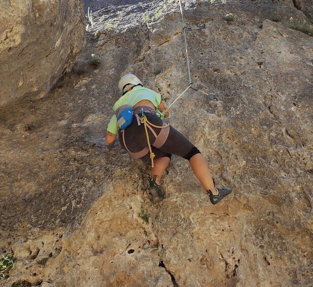 A person climbing a rocky terrain with safety harness and ropes. 1