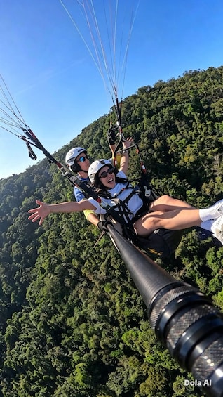 Two people paragliding with a forested mountain in the background. 5