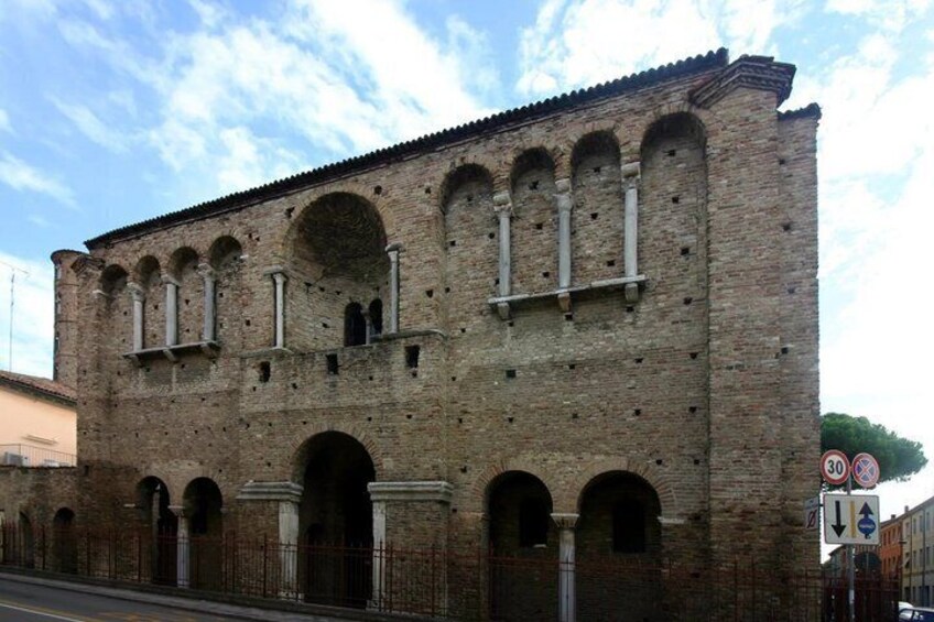A historic brick building with arched windows and a central archway. 4