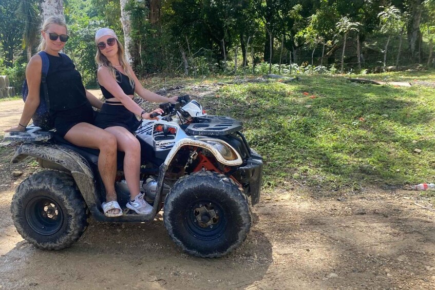 Two people on an ATV in a forested area. 5