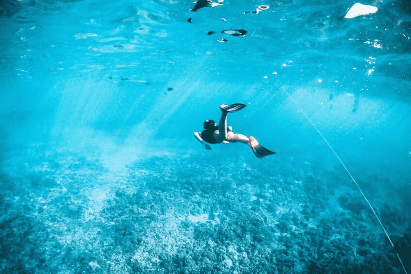 A person snorkeling underwater in a clear blue pool. 4