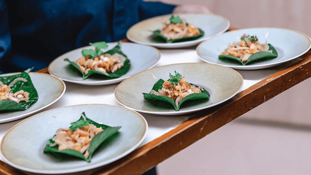 A tray of dishes with food wrapped in leaves. 2