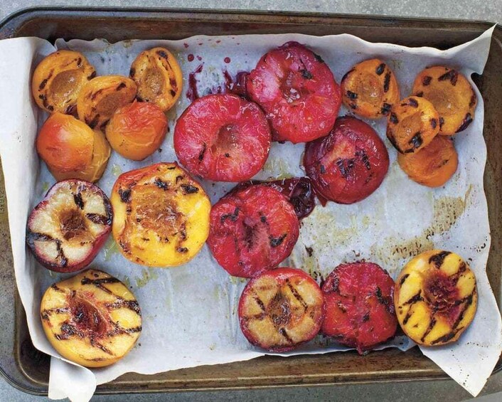 A baking tray with sliced and grilled fruits, including peaches and plums. 2