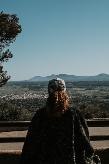 A person standing on a ledge overlooking a cityscape with mountains in the distance. 3