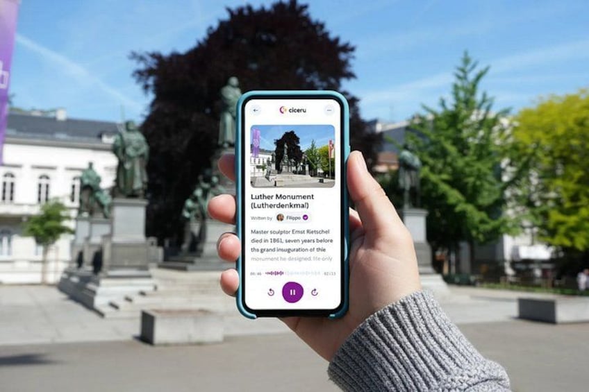 A hand holding a smartphone displaying information about the Luther Monument. 1