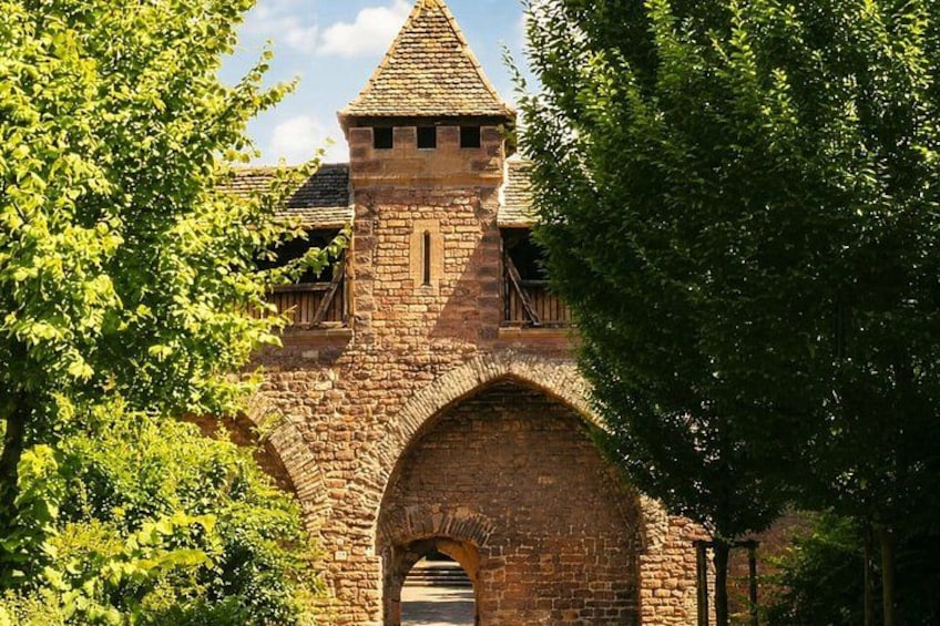 A medieval stone bridge with a tower, surrounded by lush green trees. 3
