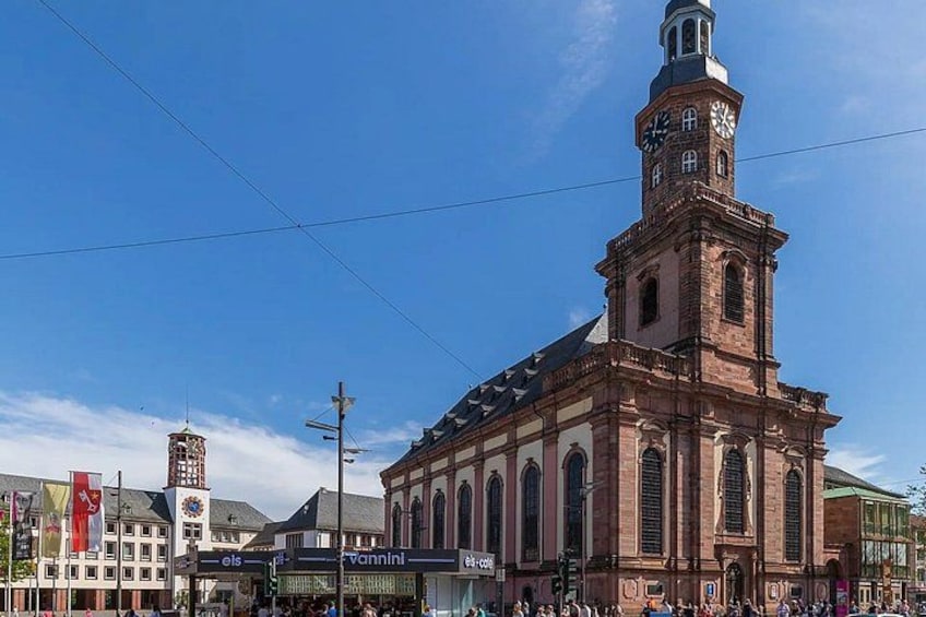A historic church with a clock tower, surrounded by a busy street with shops and pedestrians. 4