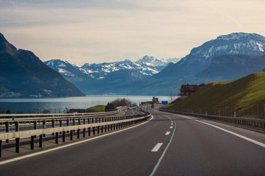 A highway curving through a mountainous landscape with snow-capped peaks in the distance. 3