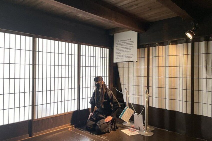 A person sitting on a bench in a room with large windows and a sign on the wall. 4