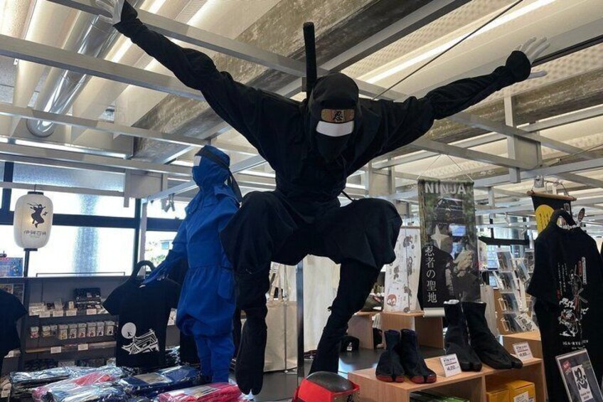 A person in ninja attire performing a high kick inside a store. 2