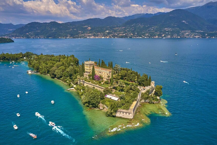 An aerial view of a historic island with a castle, surrounded by clear blue waters and boats. 3