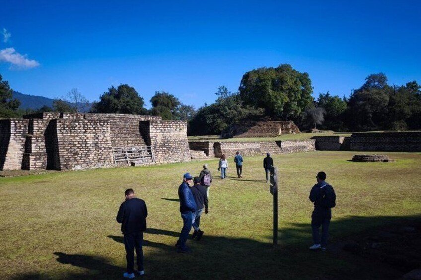 A group of people walking in a historical site with stone ruins and a grassy field. 4