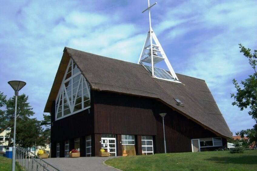A church with a triangular roof and a cross on top. 3