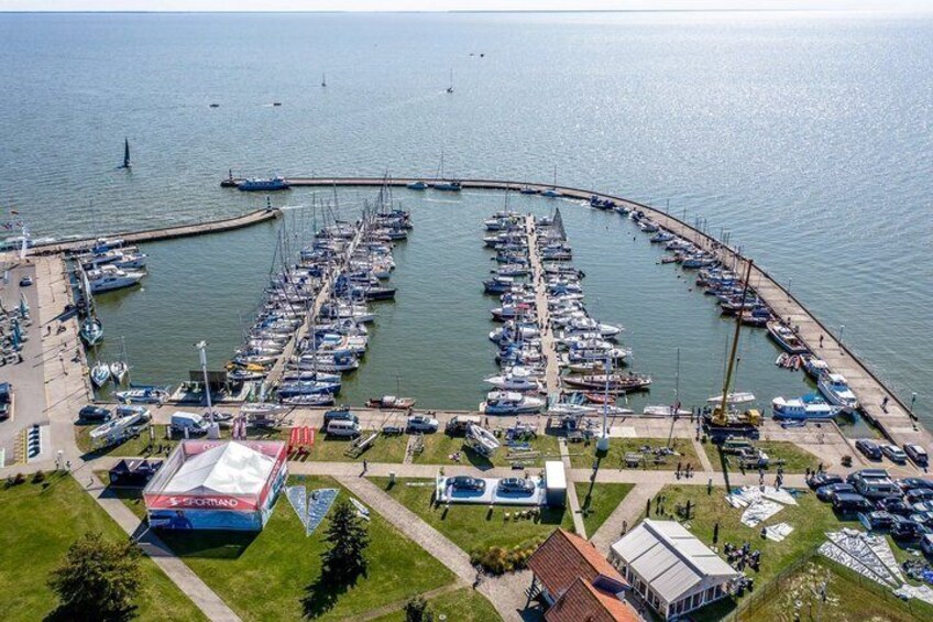 A marina with numerous boats docked, a pier extending into the water, and a large building with a red roof. 5