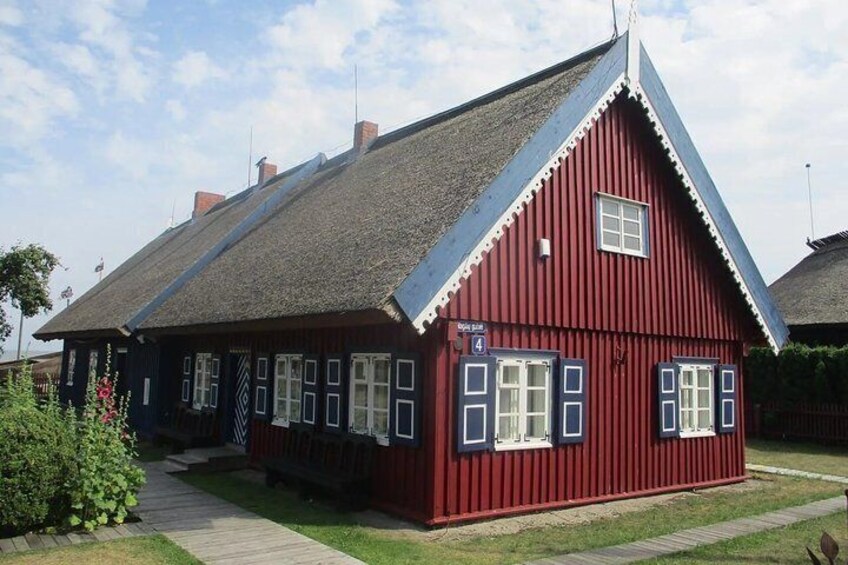 A red wooden house with a steep gabled roof and white trim. 4