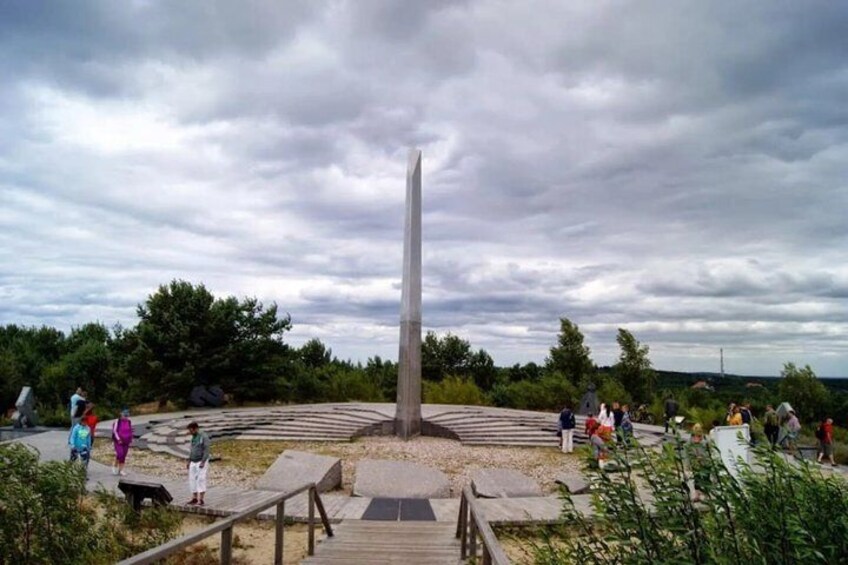 A tall monument surrounded by a circular plaza with people walking around. 2