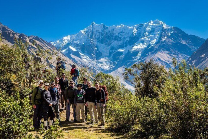 A group of hikers on a mountain trail with snow-capped peaks in the background. 2