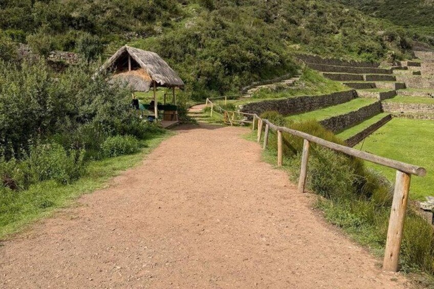 A dirt path leading to terraced fields and a rustic hut. 3