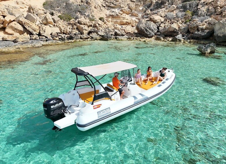A white inflatable boat with a Suzuki outboard motor on clear turquoise water. 2