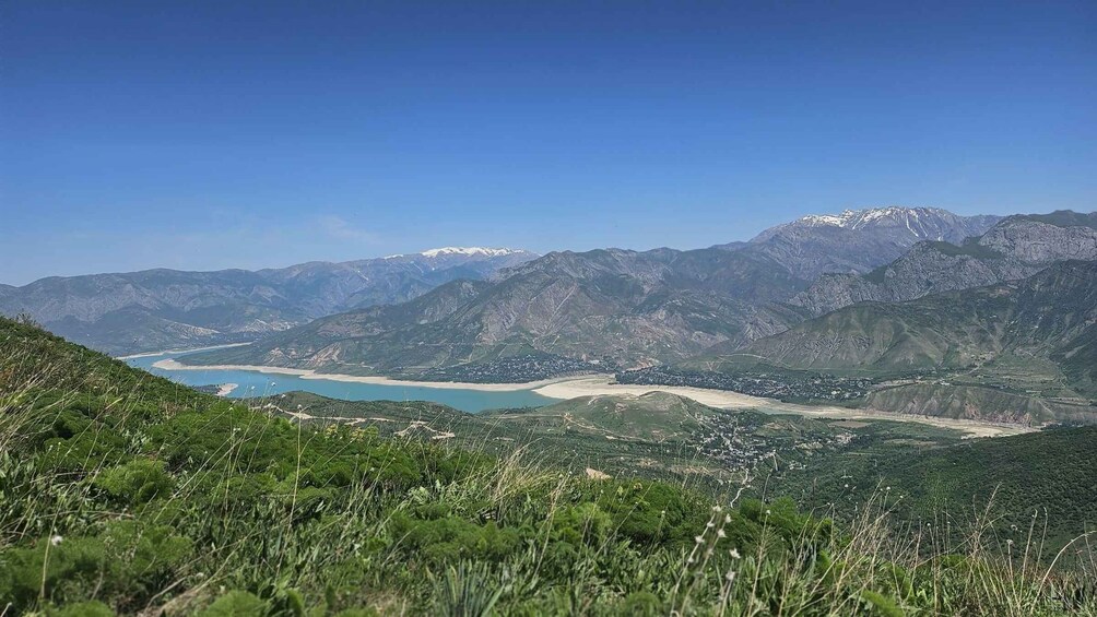 A mountainous landscape with a lake, a beach, and a town. 5