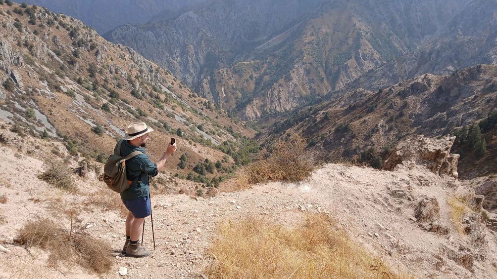 A hiker taking a photo of a mountainous landscape. 4