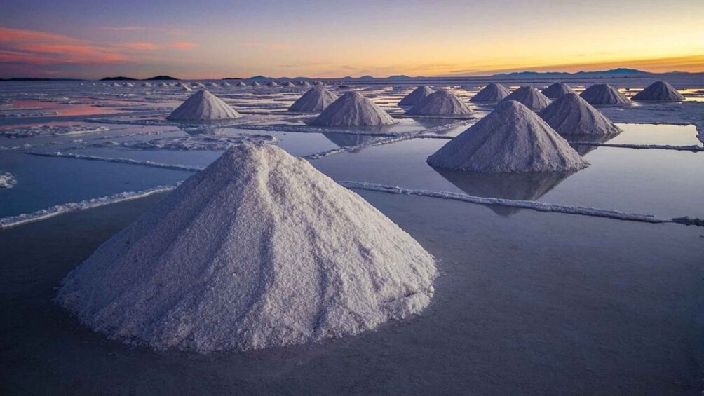 Salt formations in a flat, expansive landscape with a sunset in the background. 3