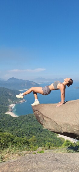A person performing a handstand on a rock with a coastal landscape in the background. 5