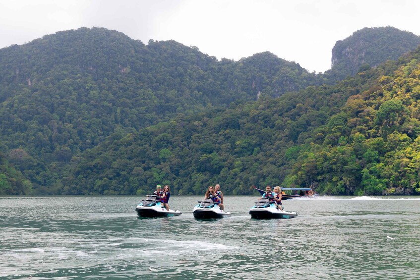 Three jet skis on a lake with a forested mountain in the background. 2