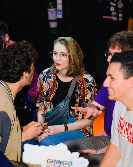 A group of people sitting at a table with a bottle of Gringo beer in the foreground. 3