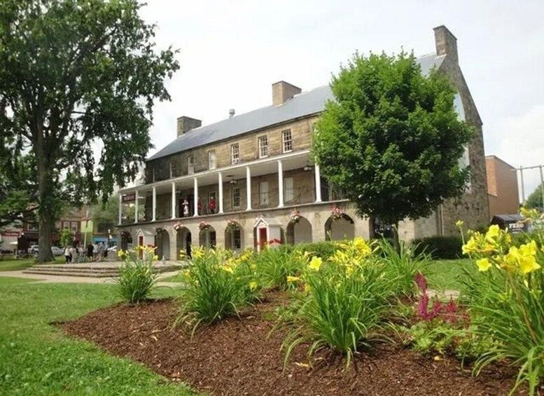 A historic building with a covered porch and a garden with yellow flowers. 5