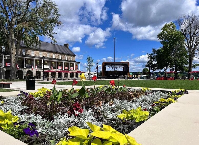 A public square with a stage, a building with flags, and a flower bed. 1